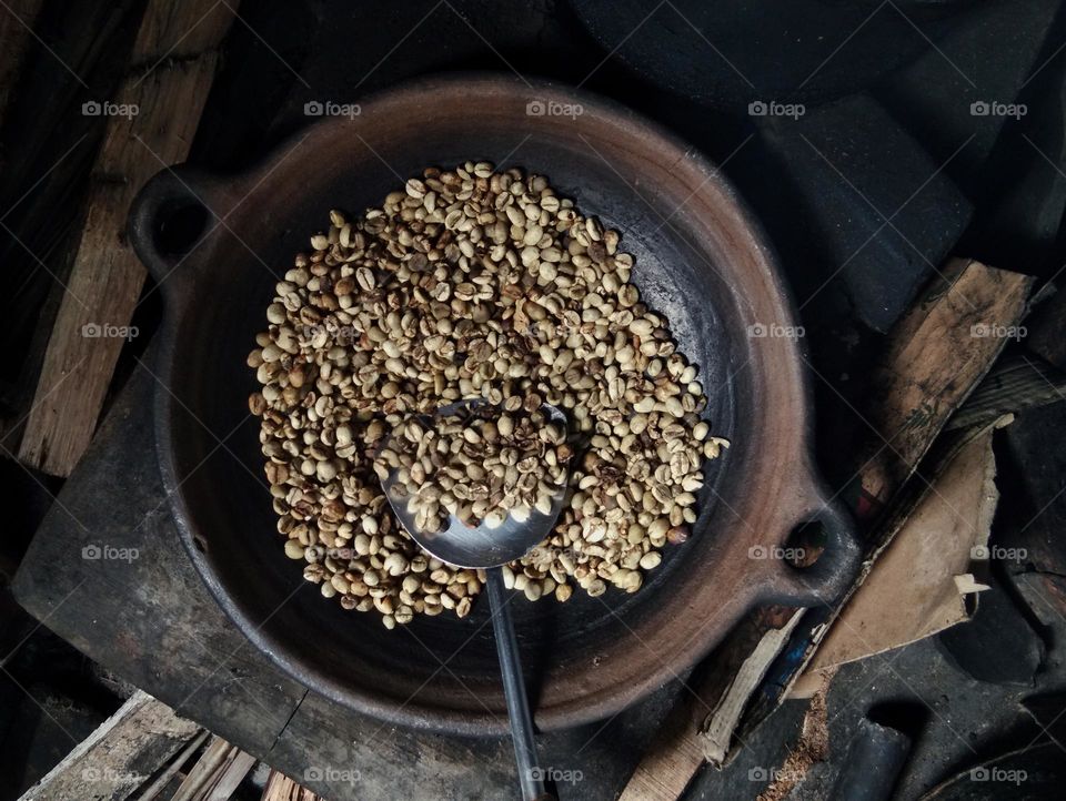 roasting coffee in traditional way. using pottery as the frying pan and furnace with firewood