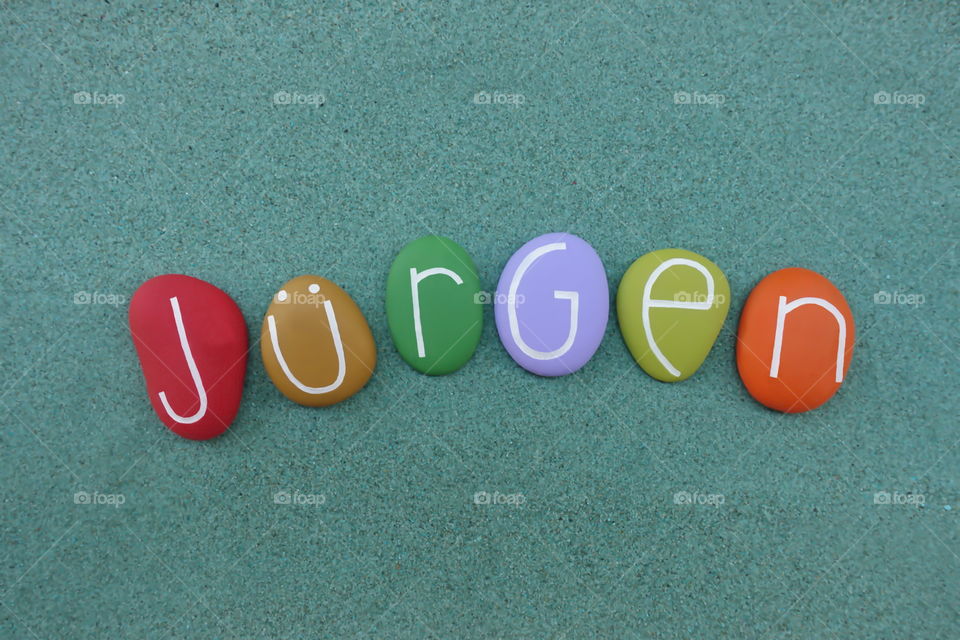 Jürgen, masculine given name composed with multi colord stones over green sand