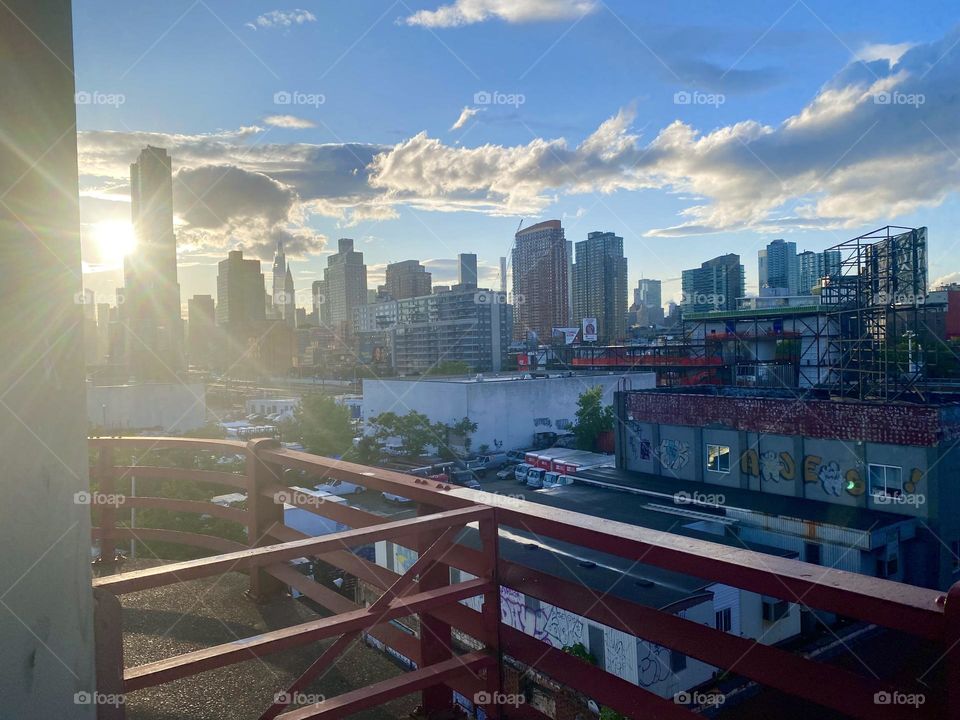 A gorgeous panoramic view of “Long Island City” can be enjoyed from the “Pulaski Bridge” at “Newtown Creek”, especially when a bright sunny day comes to an end and the setting sun reflects off the clouds above. 2023. Hypnotic Productions