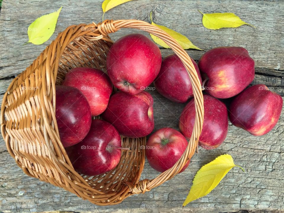 Red apples fallen down from the basket on wooden table