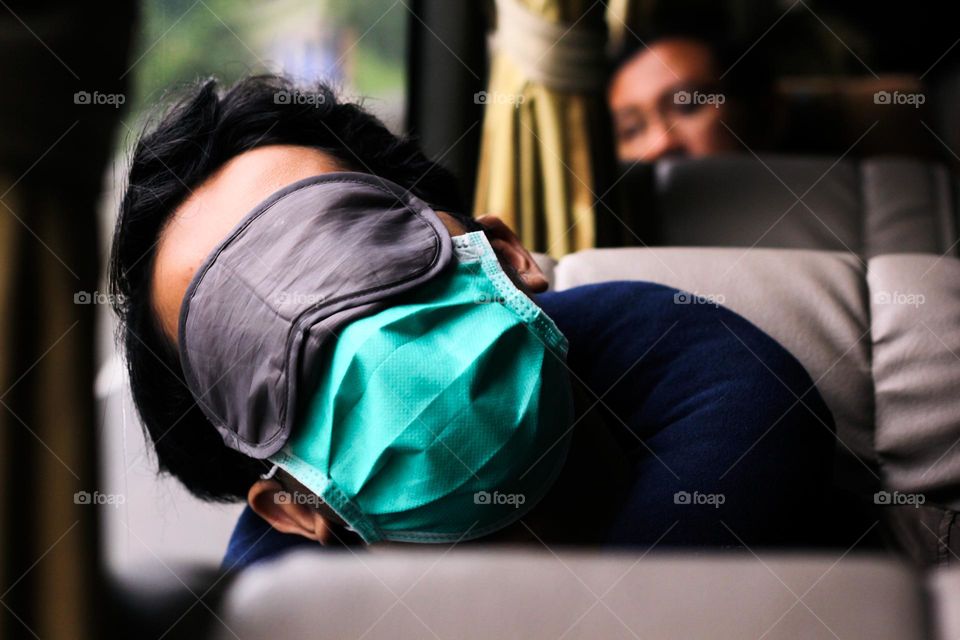 Portrait of a bus passenger sleeping in a passenger seat, whether blindfolded or not, Yogyakarta, Indonesia.