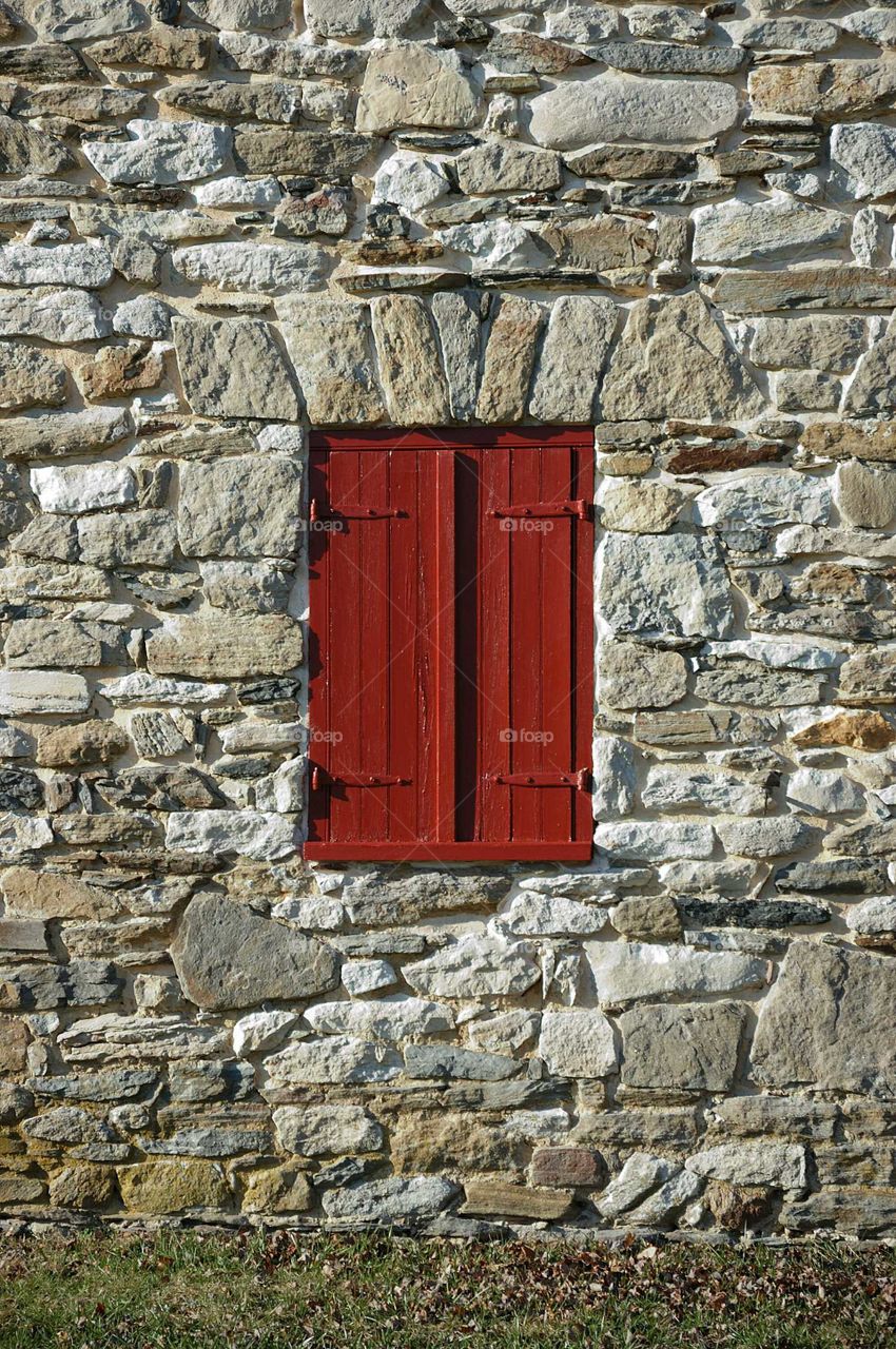painted red shutters on stone wall