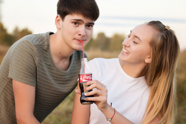 Girl looking at boy drinking cold drink