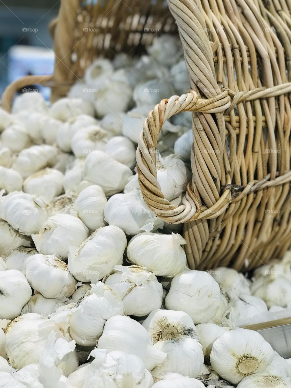 A flatten bamboo basket full of garlic.