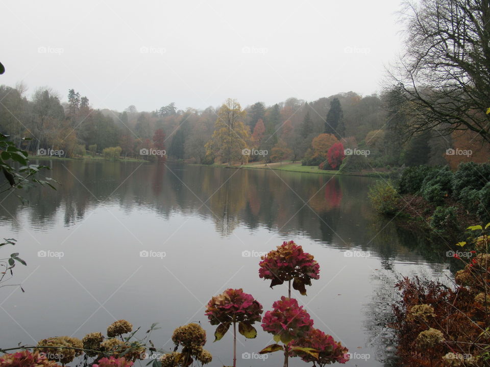 Stourhead lake with a grey sky and a little autumn colouring