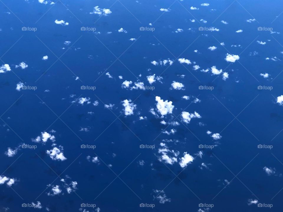 clouds from airplane in clear blue sky on ocean