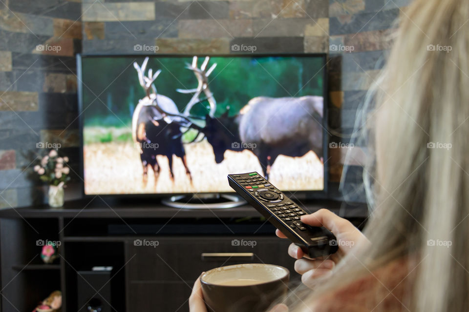 Girl with remote control in hand watching television