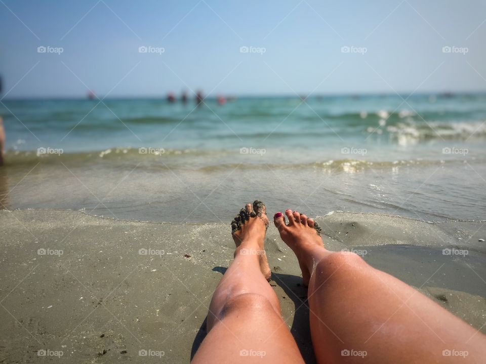 Woman's legs on the sand near the sea