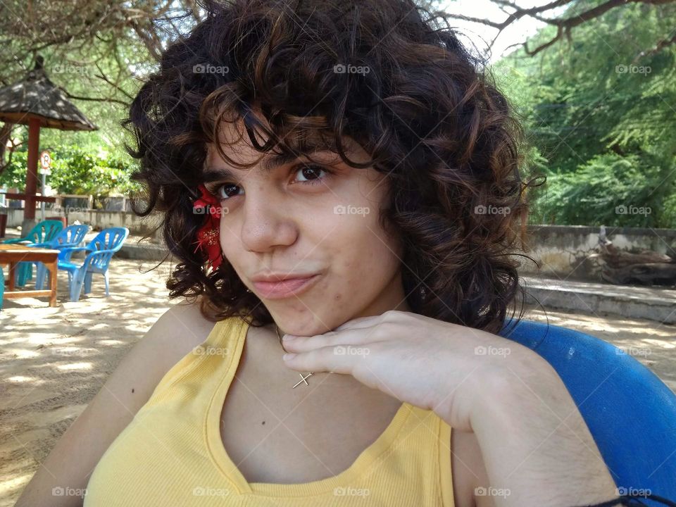 Girl making fun with a flower in the hair by the beach