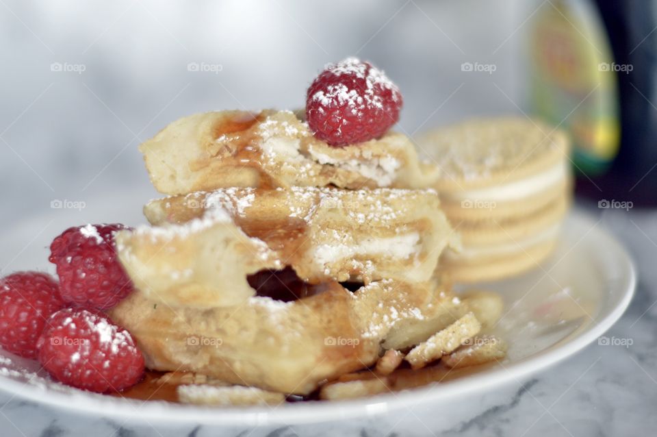Golden double stuff Oreo cookies and a waffle with raspberries and powdered sugar
