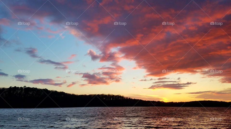 sun setting on the lake with pink clouds.