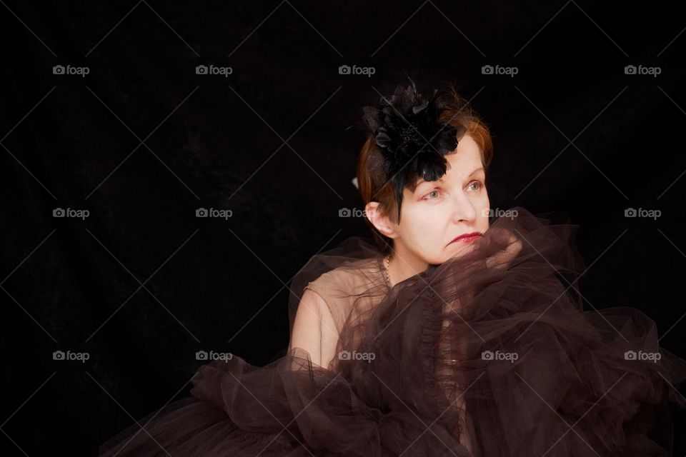 Woman sitting against black background