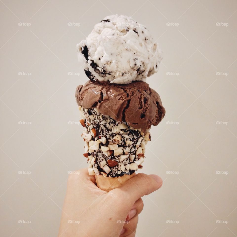 Person holding double ice cream scoops with nuts cone