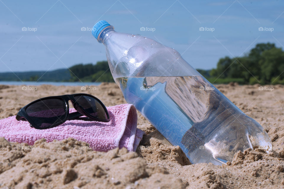 Bottle with clean drinking water lies on the beach