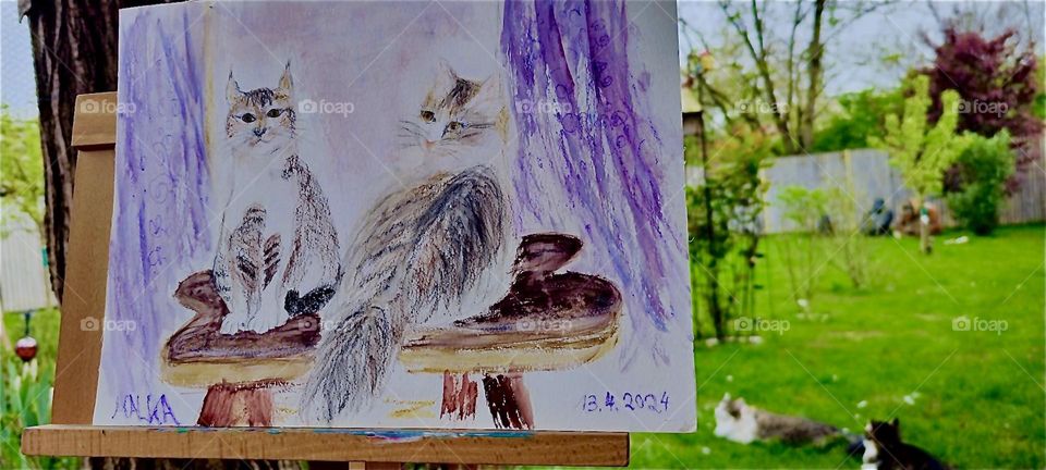 This is a hand drawn portrait of “Roukey” and “Linda”, two sibling cats that live in rural “Bavaria”, Germany displayed on an easel on the terrace overlooking the garden. 2024. Hypnotic Productions