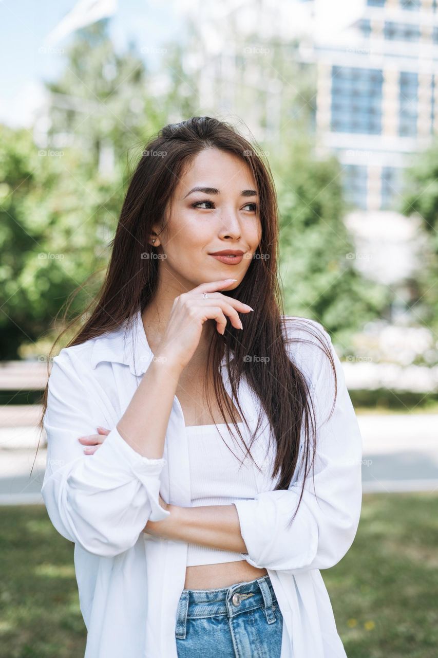 Portrait of young asian woman student with long hair in city park