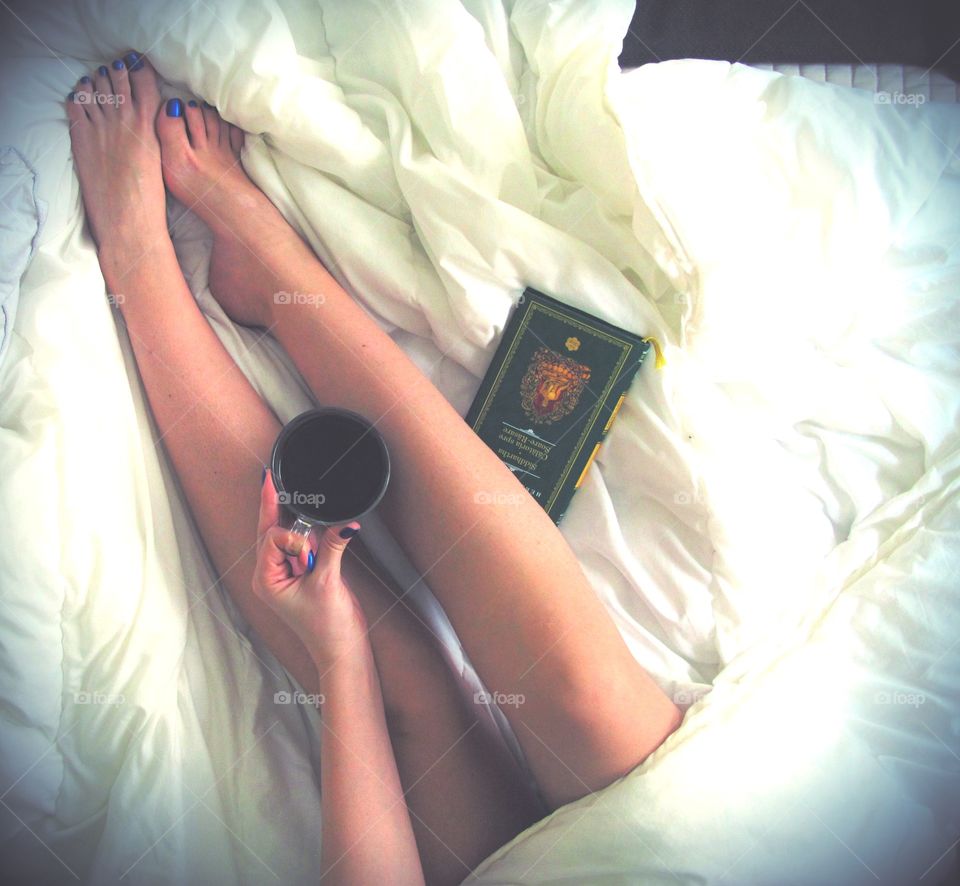 Woman sitting on bed holding coffee cup