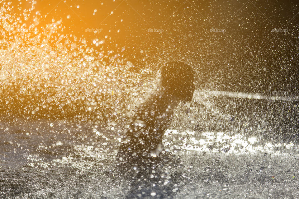 Kid refreshing in the fountain in the city, silhouette