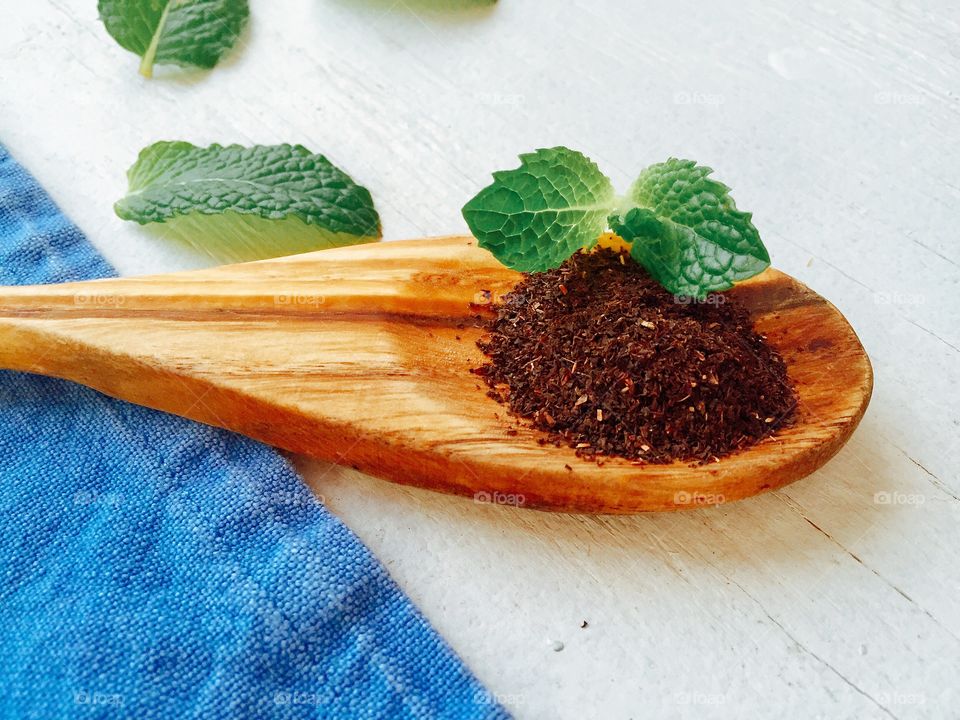 Wooden spoon on soil with mint leaf