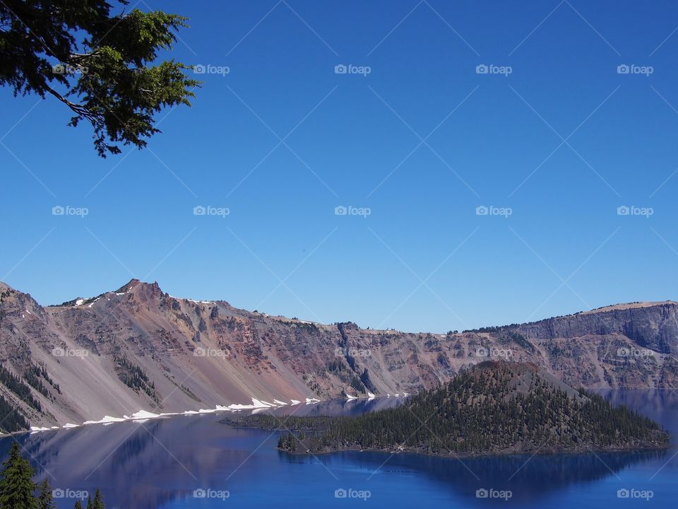 Wizard Island reflecting in the rich blue waters of Crater Lake in the forests of Southern Oregon on a sunny summer morning. 