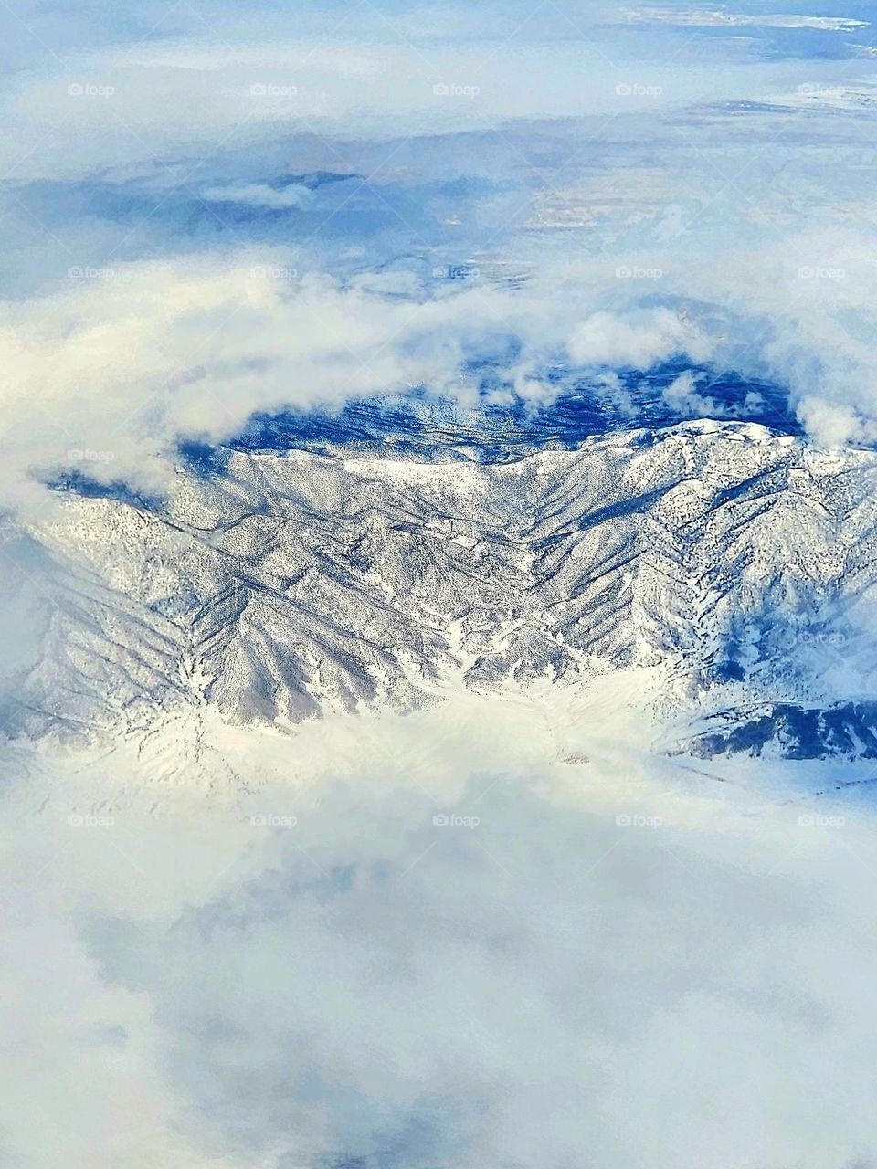 Flying at 38,000 feet above solid clouds, there is a break when tall snow covered mountains break through