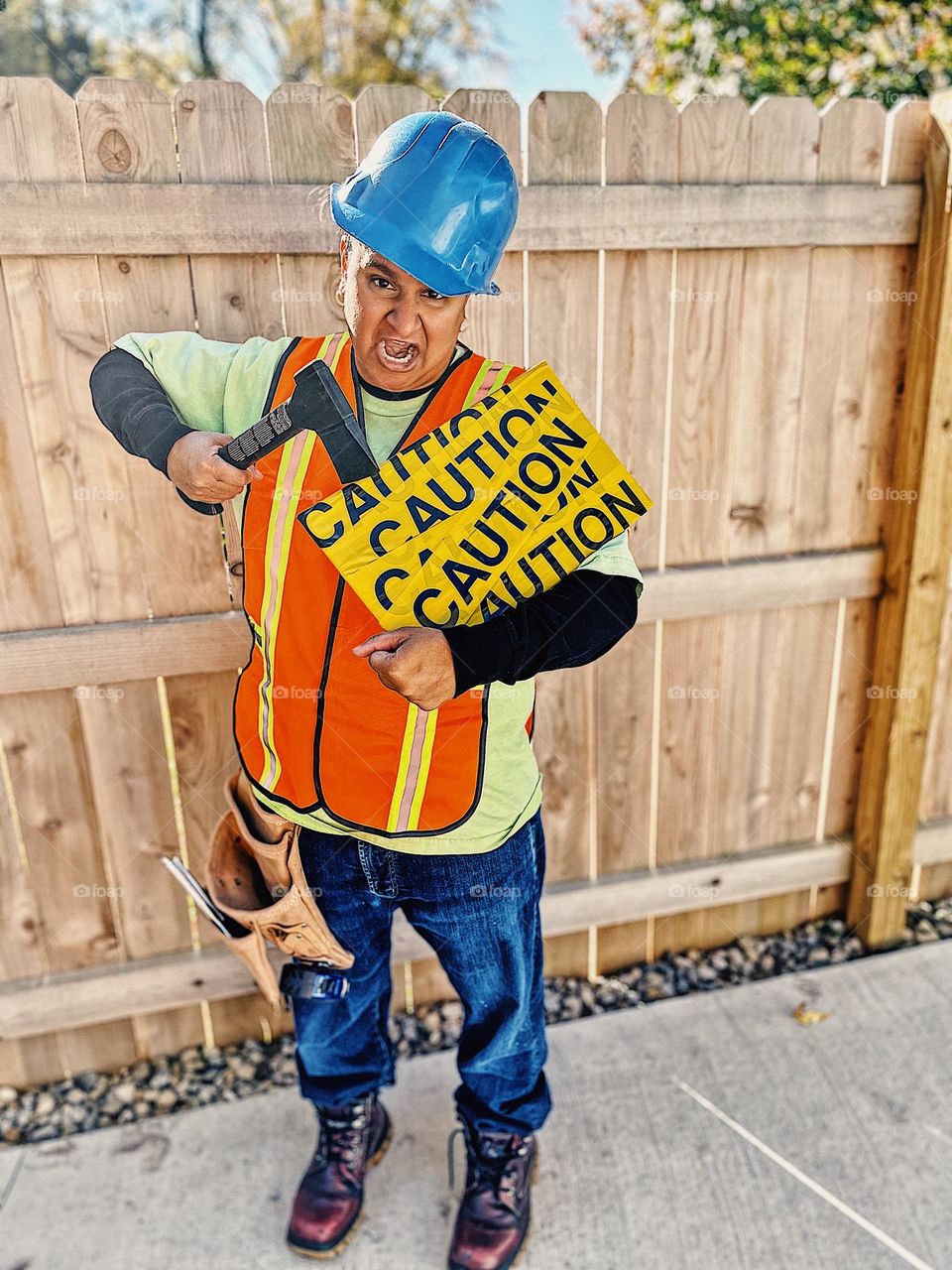 Portrait of a woman construction worker, woman dressed as a construction worker, woman construction worker with caution sign, funny portrait of a woman, woman being silly with tools, Halloween costume on a woman