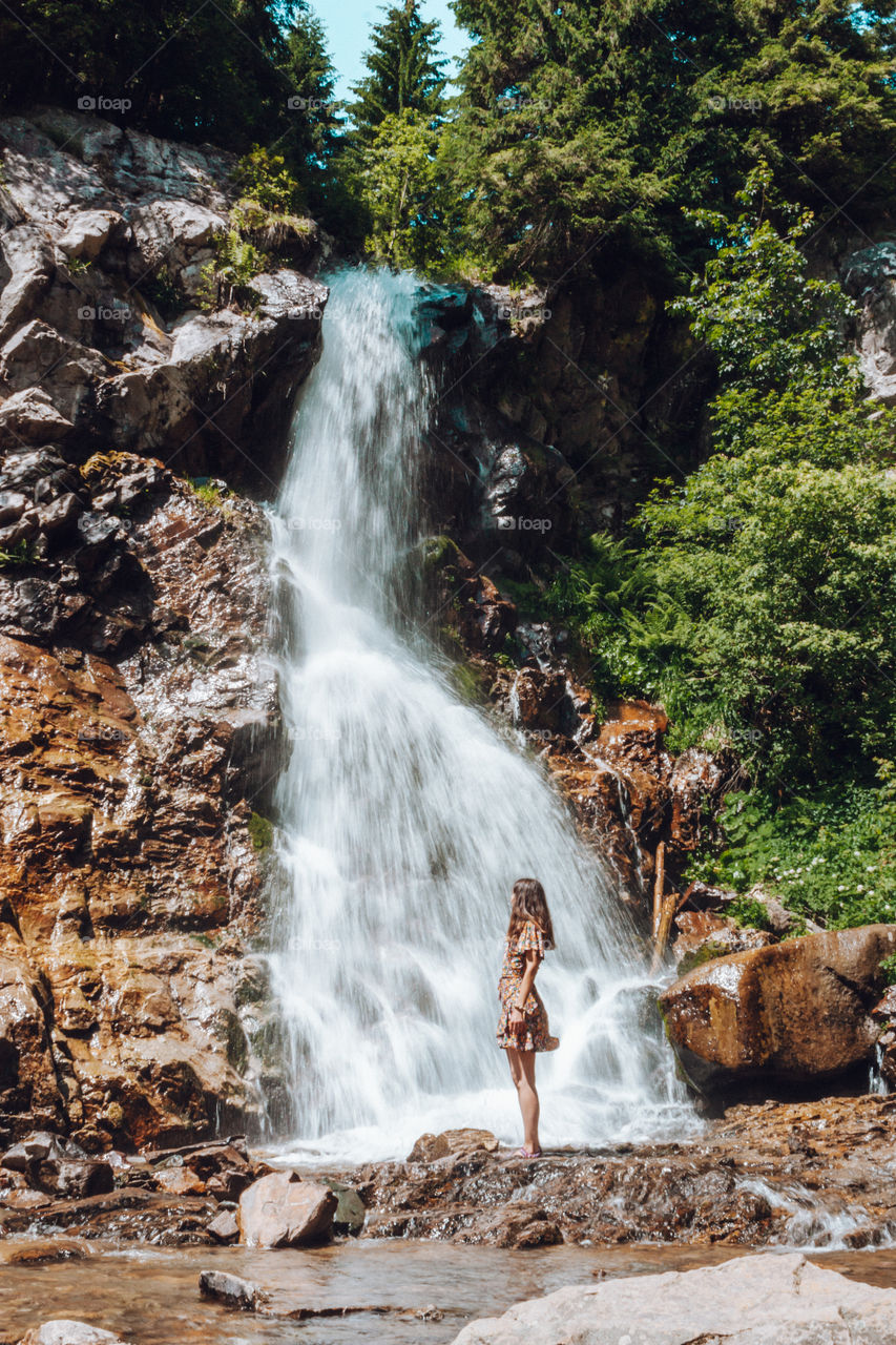 woman sitting next to an amazing waterfall