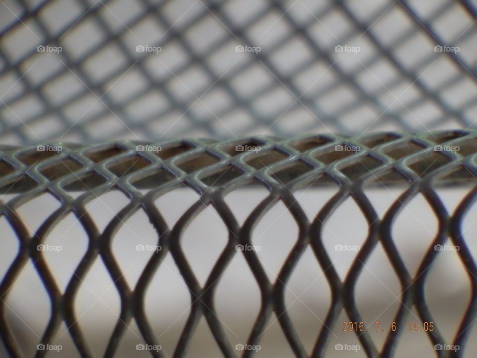 Close-up of grey criss cross metal bench.