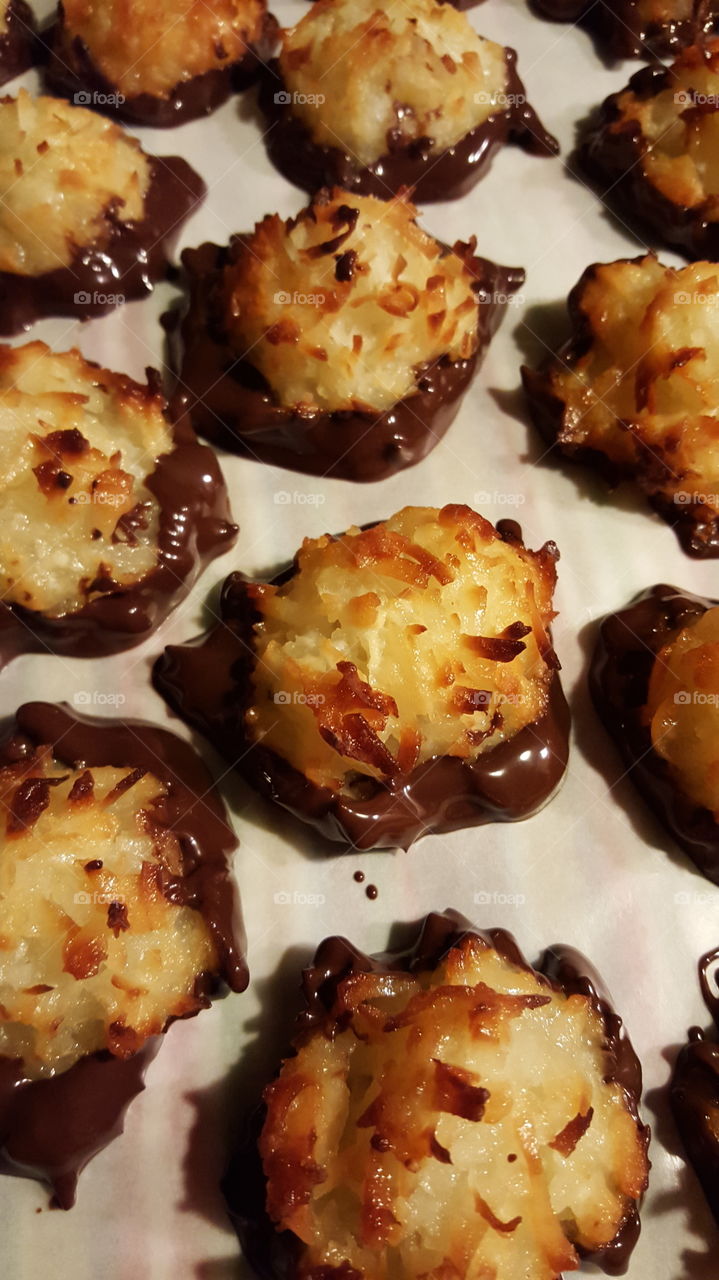 Golden brown coconut cookies freshly dipped in dark chocolate. It's hard to resist eating one before they have cooled.