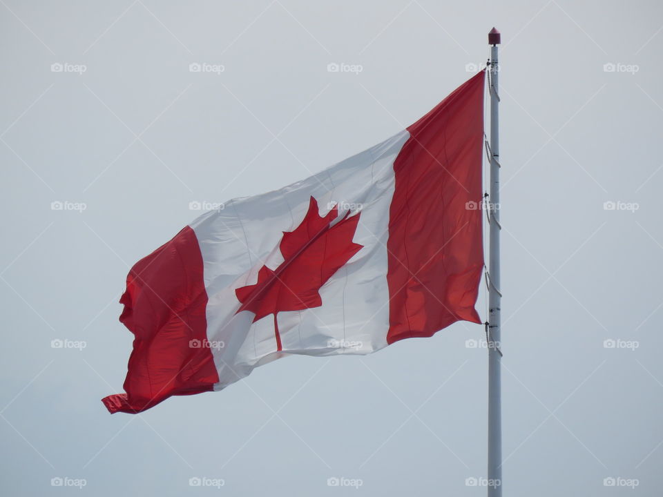 A Canadian flag in the wind on a cloudy day. 