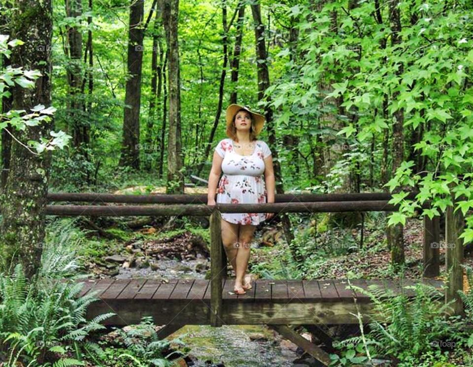 A woman standing on a bridge in the middle of the forest 
