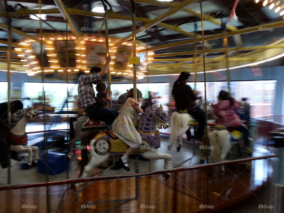 Carousel Ride. A father and son abd other people ride a carousel.