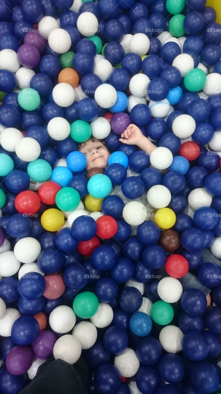 Cute little boy in colorful ball pool