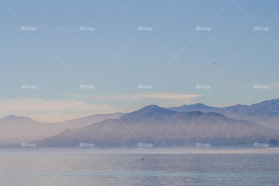 Mountain range seen in the distance across the Salton Sea in Riverside and Imperial counties, with the mist rising off the water giving a watercolor effect