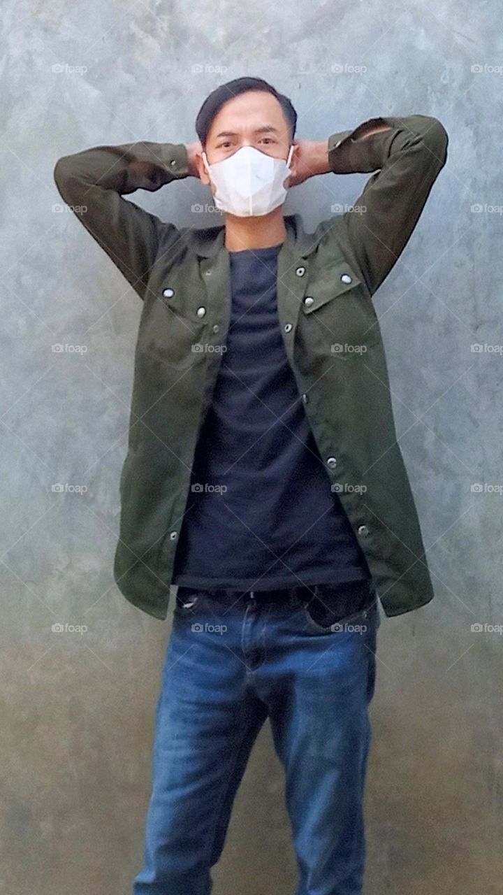 Stylish young man surrenders in front of the wall