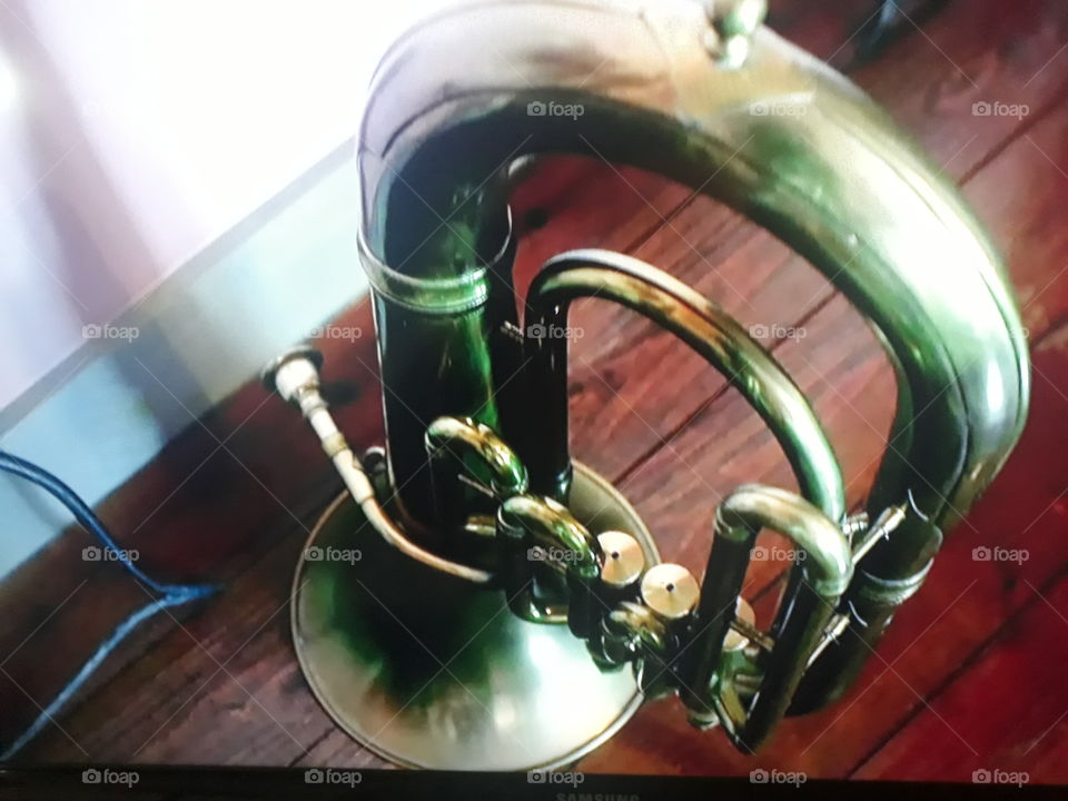 one of the most beautiful instruments of antiquity in golden color standing on brown wooden floor