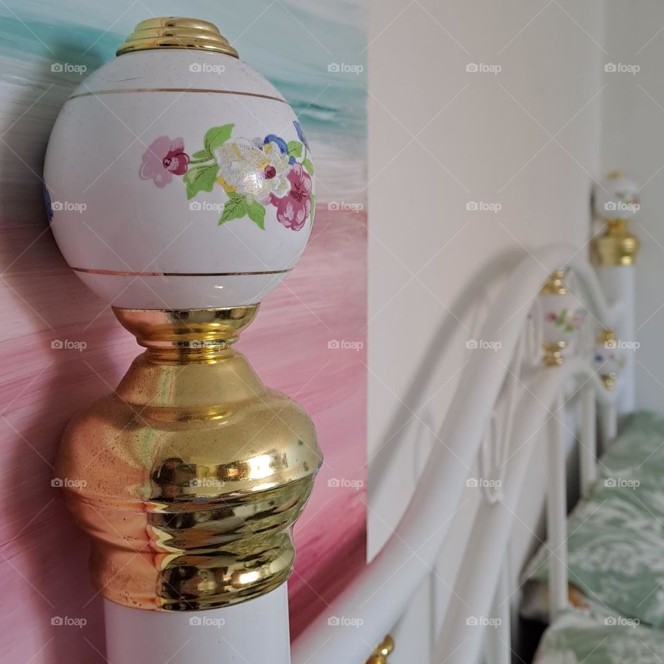 pretty white headboard with gold knob in bedroom. bed painting in wall
