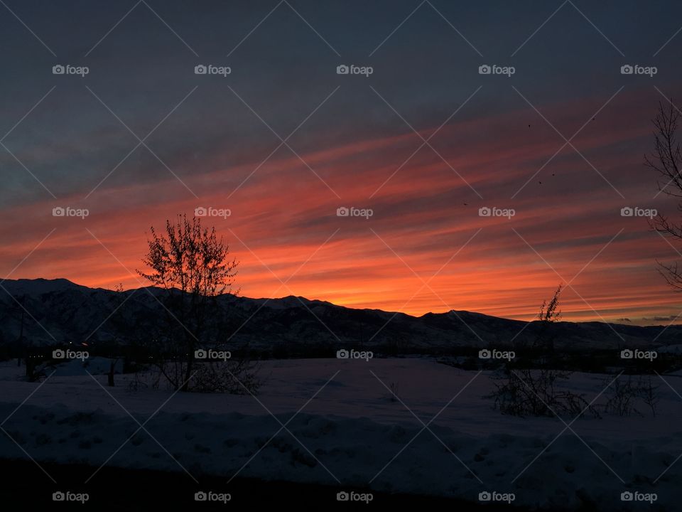 A beautiful sunset about a snowy mountain and field. 