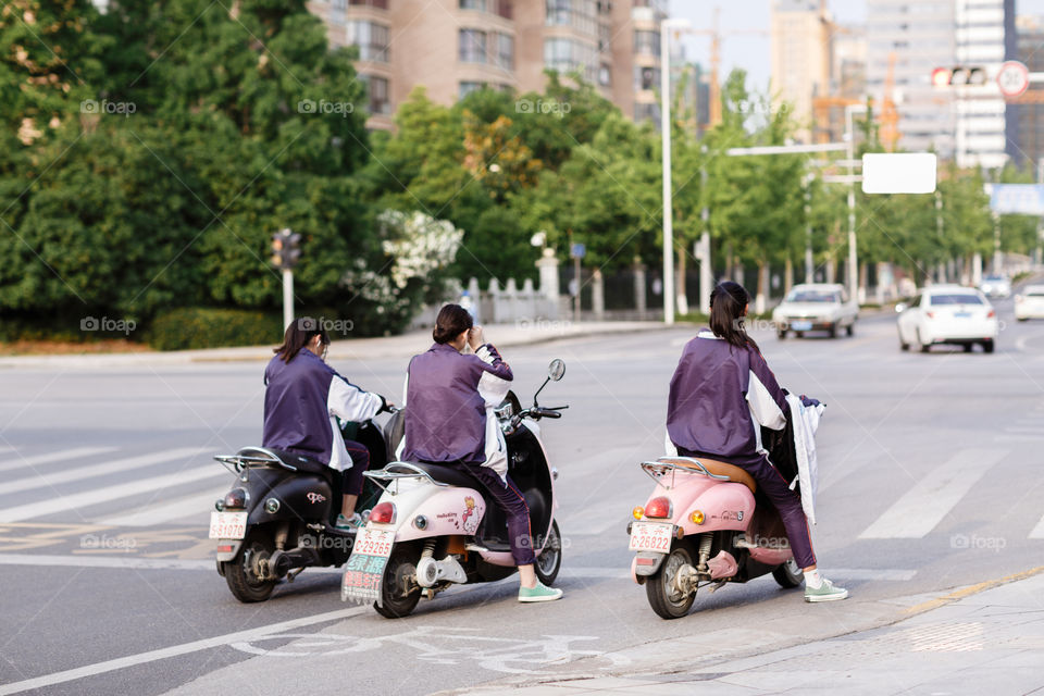 Three girls riding on scooters 