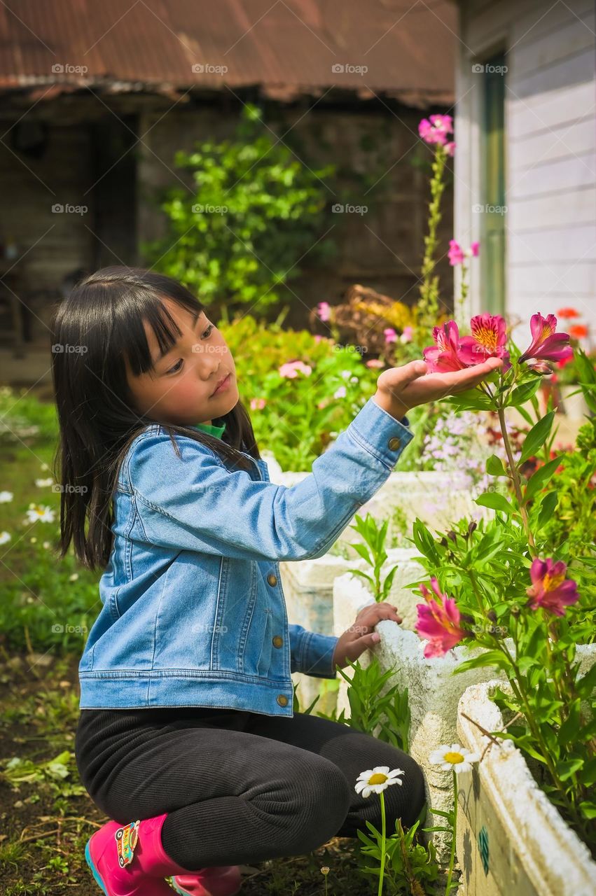 Here comes the spring, a time to love and adore the beauty of nature, a little girl feeling the softness of the flowers.