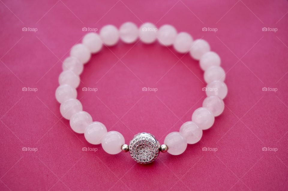 White bead bracelet on pink background