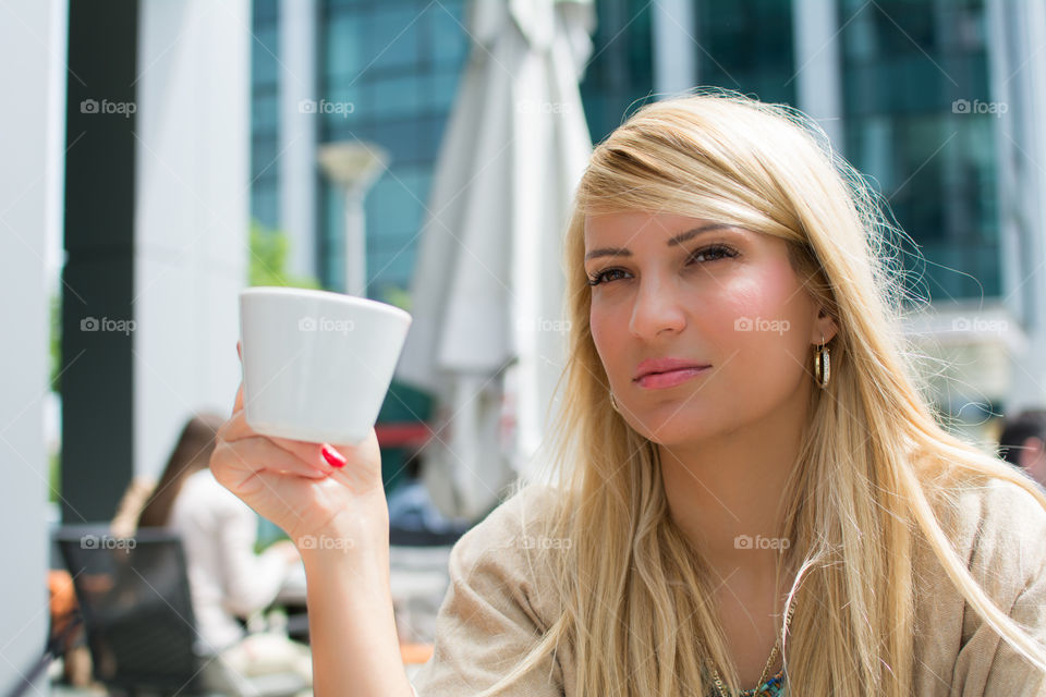 Pretty woman sitting in restaurant with coffee cup in hand