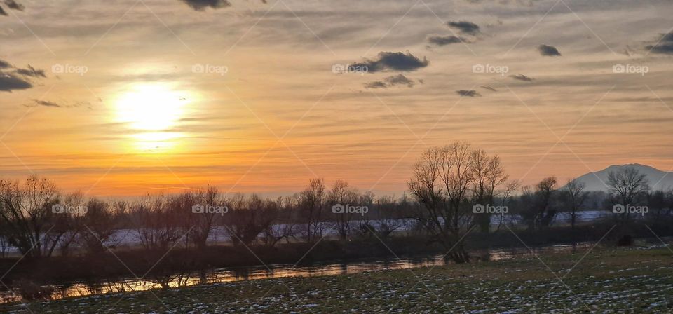 Beautiful view of a sunset over horizon and sunlight reflecting on the flowing river