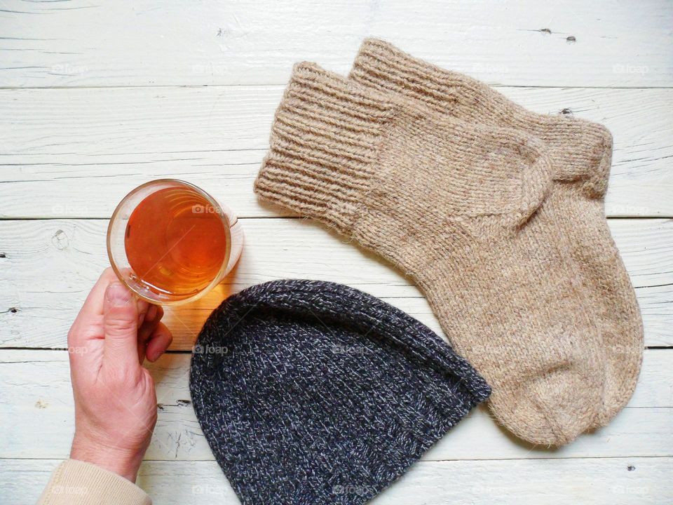 A woolen knitted socks, a hat and a cup of tea