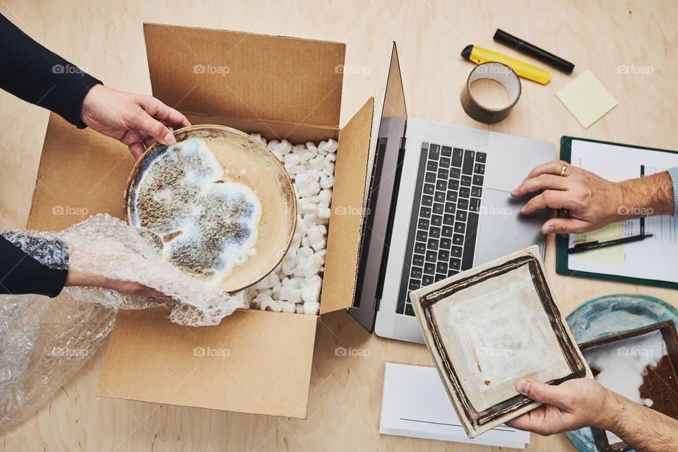 Business owner packing online order to delivery to customer. Preparing parcel box with ceramic plate product from online shop