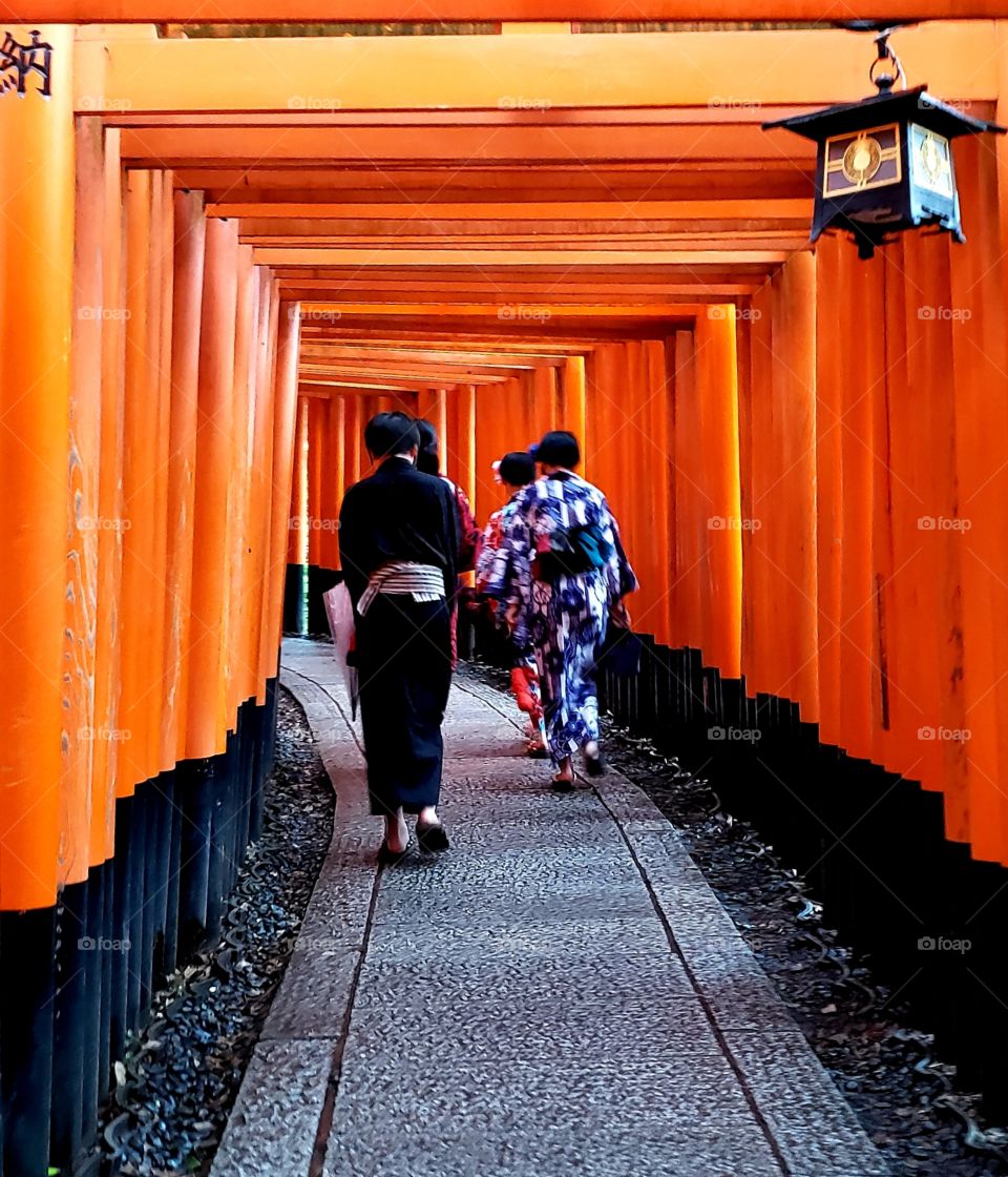 Student on holiday strolling through the thousands of tori gates in traditional wear.