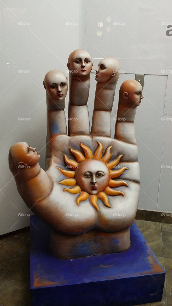 sculpture with sun face in faces on the fingers