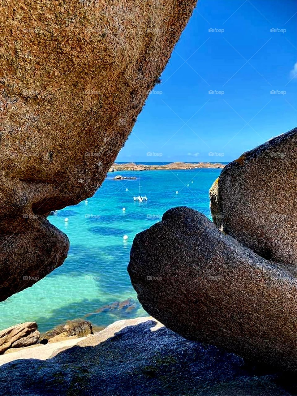 View of the sea and the boats through the rocks in Trégastel