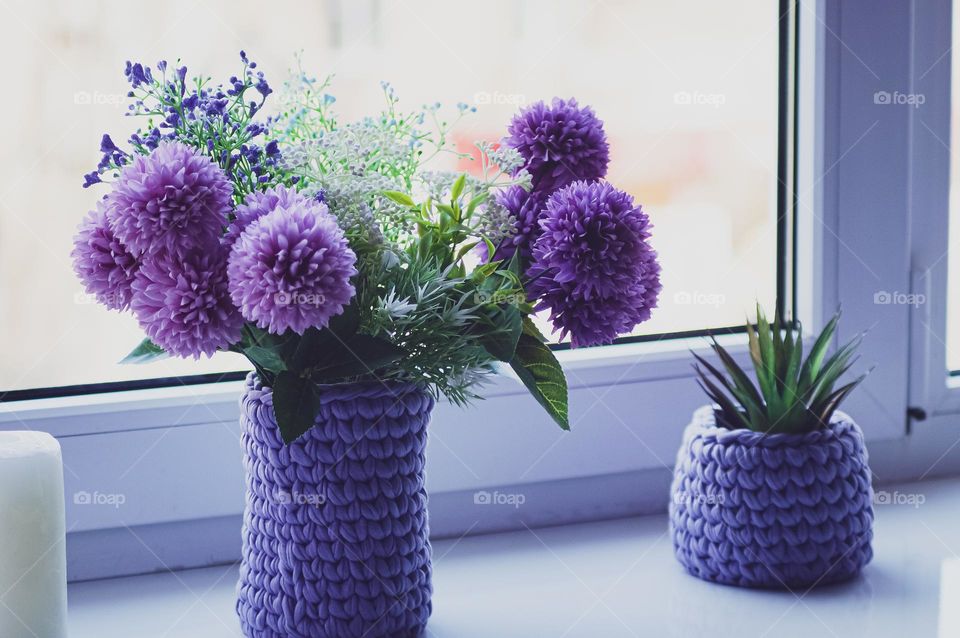 Purple flowers in a vase by the window