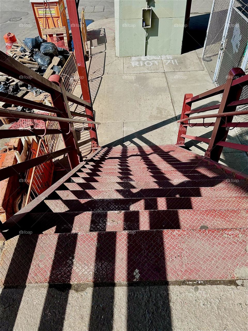 This intricate mix of structures, patterns, shadows and shapes meanders down the red metal staircase of the “Pulaski Bridge” at “Newtown Creek” in LIC, Queens. 2024. Hypnotic Productions
